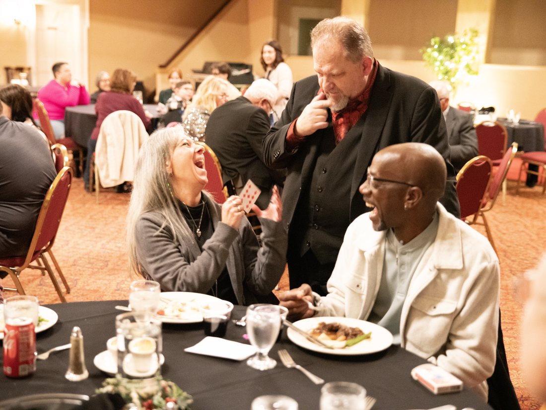 Guests reacting to Carroll Baker's close-up magic at a company event